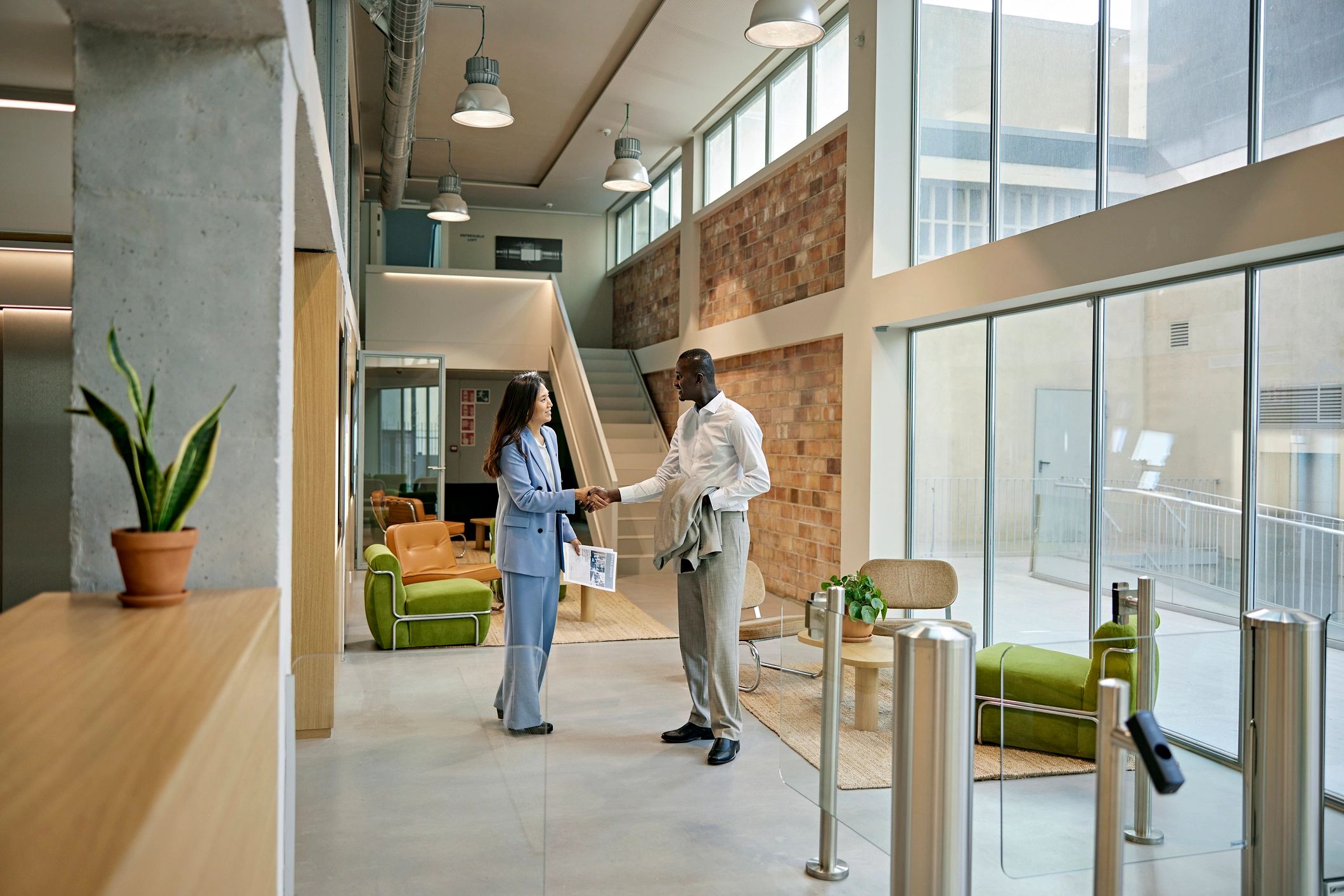Real estate agent greeting a client in a modern building lobby